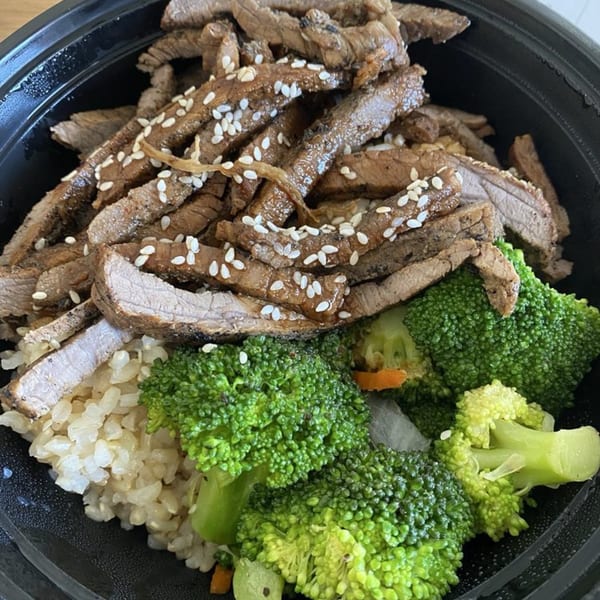 Hungry Hawaiian's teriyaki beef with sesame seeds, broccoli, and brown rice in a black bowl.